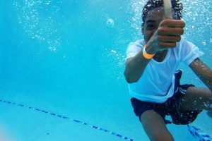 Under water photography of boy showing thumb